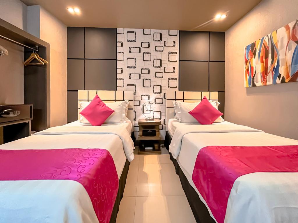 two beds in a hotel room with pink pillows at Eloisa Royal Suites in Mactan