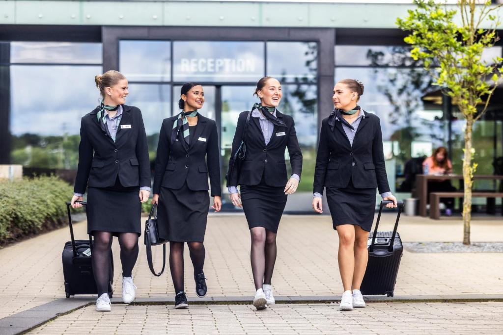 a group of women walking down a sidewalk with luggage at Airport Hotel, Billund in Billund
