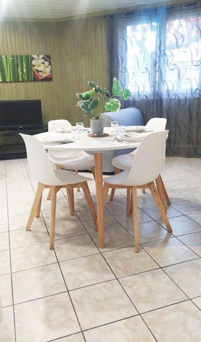 - une table avec des chaises blanches et une plante en pot dans l'établissement Studio Cosy au Calme, RER-2arrêts Stade-25minParis, à Stains