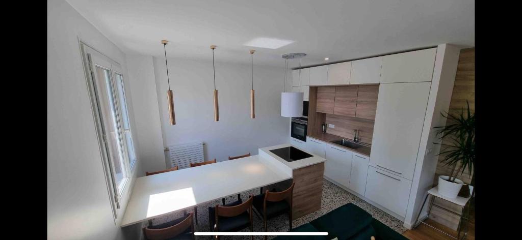 une cuisine avec un comptoir blanc et un évier dans l'établissement Charmant appartement 65m2 mairie de saint ouen - carrefour pleyel, à Saint-Denis
