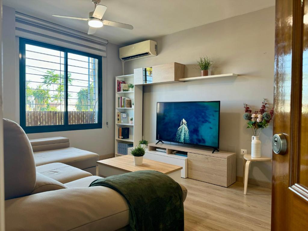 a living room with a couch and a flat screen tv at Beach Apartment, Torre Benagalbón in Torre de Benagalbón
