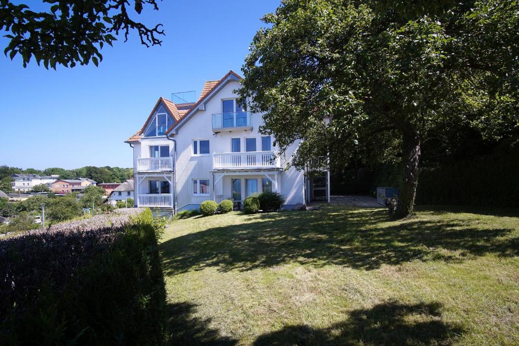 a large white house with a tree in the yard at Die Ferienwohnung Ostseepanorama in der Villa Joksch in Lohme