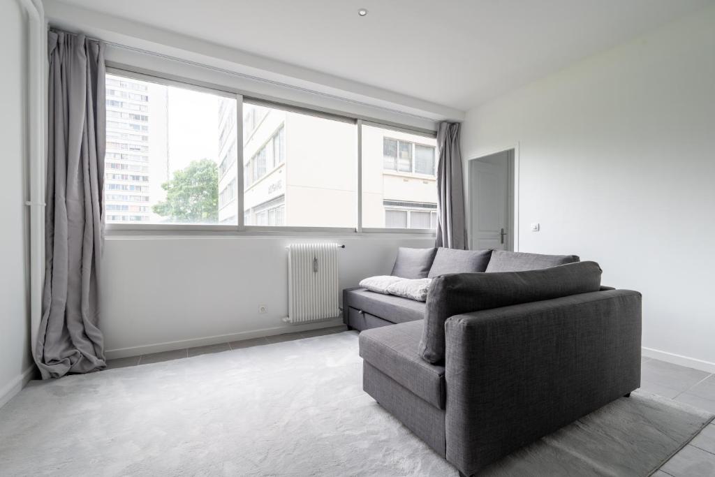 un salon avec un canapé et une grande fenêtre dans l'établissement Appartement 2 Chambres - Porte de Choisy, à Paris
