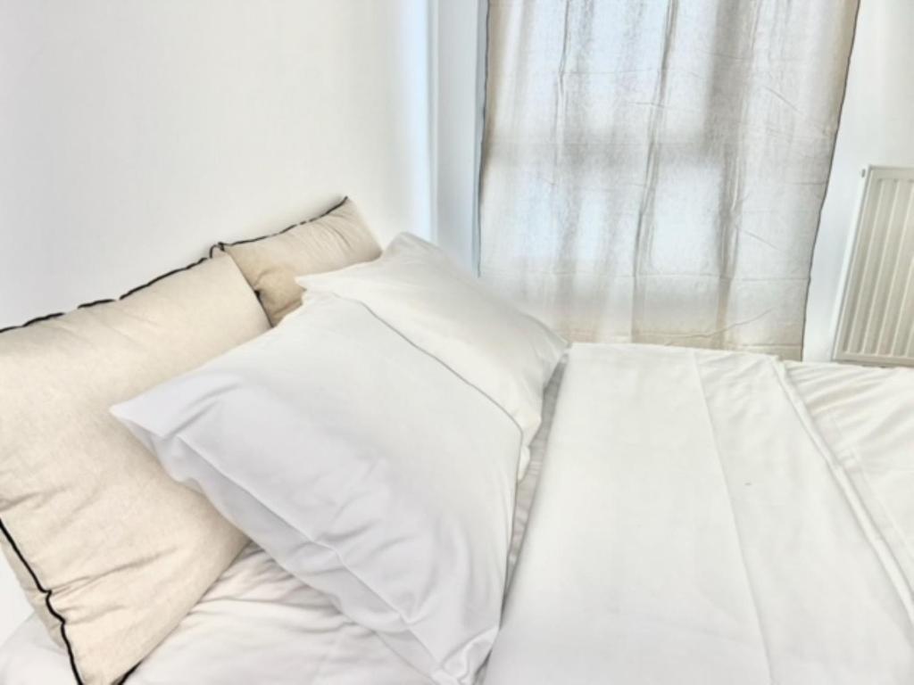 un canapé blanc avec deux coussins devant une fenêtre dans l'établissement M43 Marquer Joli T3 proche du centre ville d'Annemasse, à Annemasse