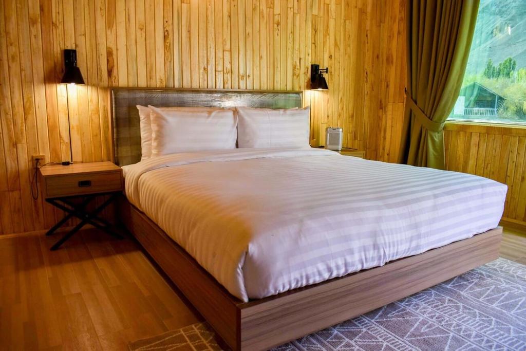 a bedroom with a large bed with wooden walls at The Rover by Roomy, Phander Gilgit Baltistan in Serbal