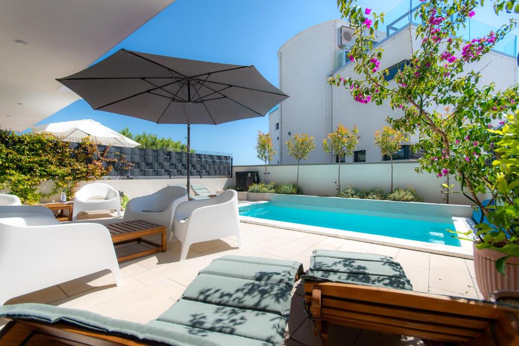 a patio with an umbrella and a swimming pool at Beachfront Villa Taris with Seaview in Privlaka