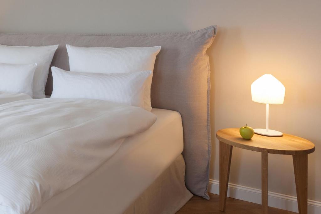 a bed with a table with a lamp on it at Vju Hotel Rügen in Göhren