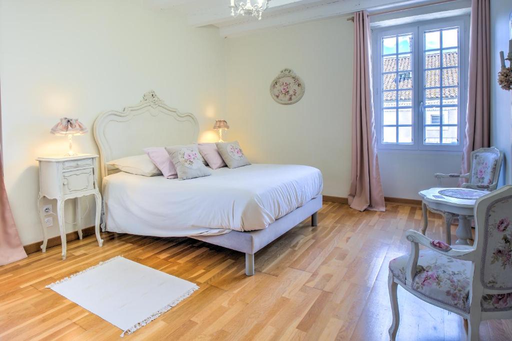 une chambre blanche avec un lit et une chaise dans l'établissement Gite Le Petit Saint Jean, à Saint-Jean-de-Côle