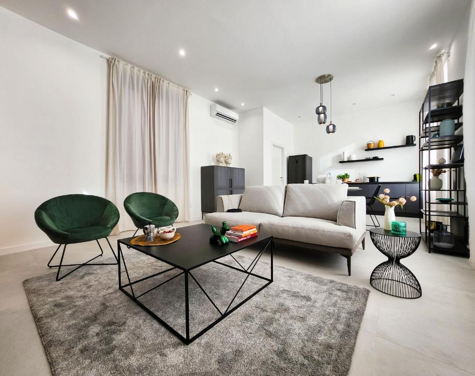 ein Wohnzimmer mit einem Sofa und zwei grünen Stühlen in der Unterkunft Matteotti Royale Apartments in Syrakus