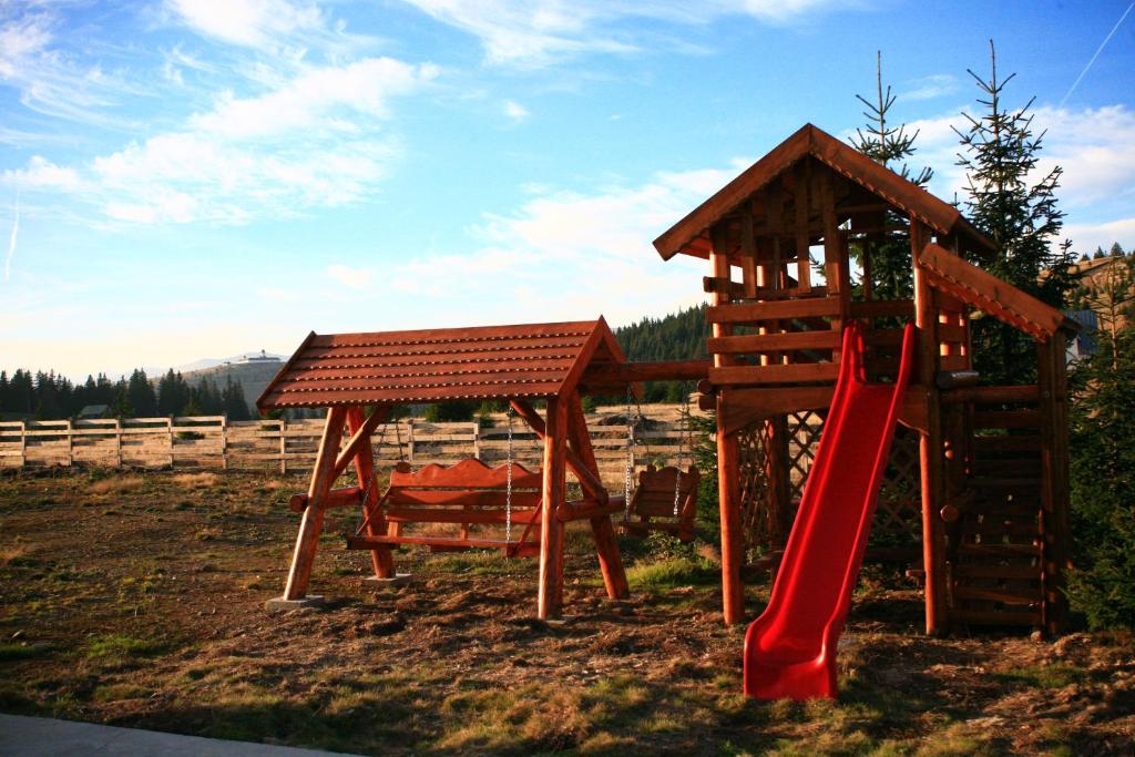 un parque infantil de madera con un tobogán y un tobogán rojo en Pensiunea Muntele Alb, en Horezu