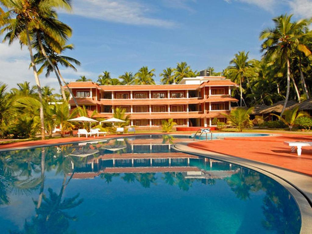 a resort with a swimming pool in front of a building at Abad Harmonia Ayurvedic Beach Resort in Kovalam