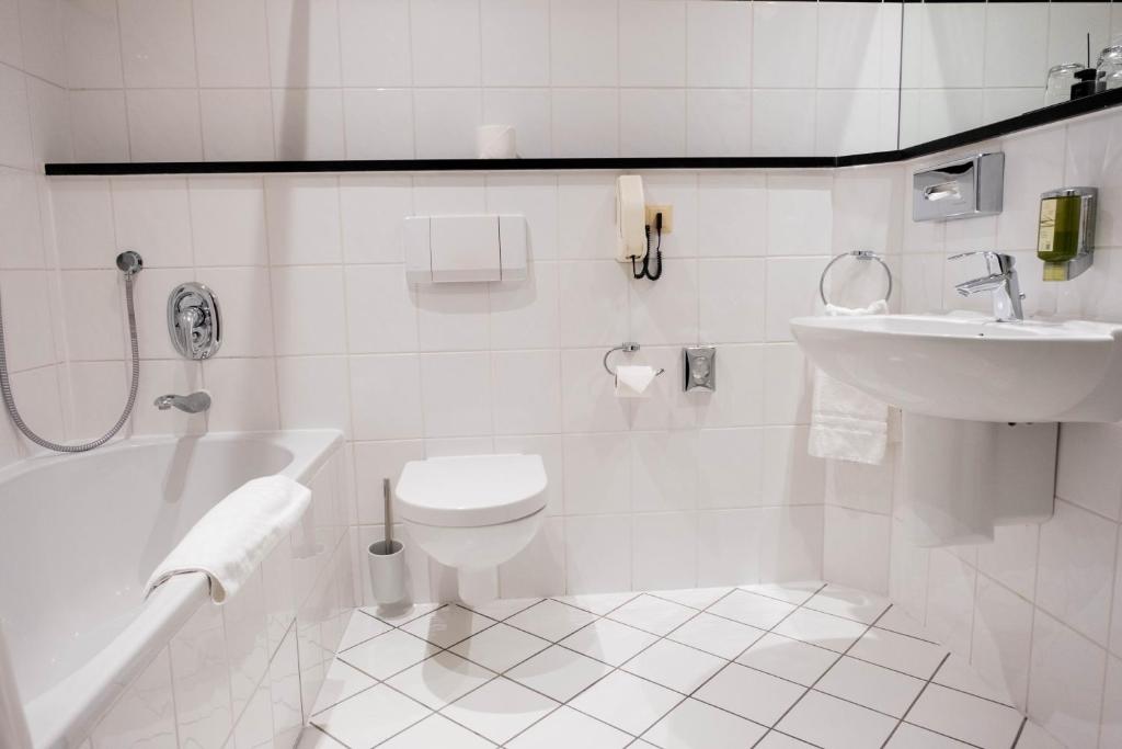 ein weißes Badezimmer mit Toilette und Waschbecken in der Unterkunft Hotel Ottheinrich in Weinheim