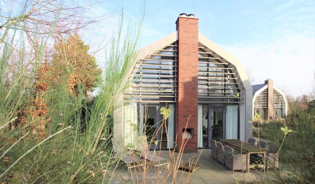 a brick and glass house with a chimney at In de Duinpan in Egmond aan den Hoef
