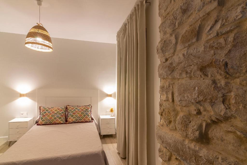 a bedroom with a bed and a stone wall at Vivienda Turística CASA QUEVEDO in Úbeda