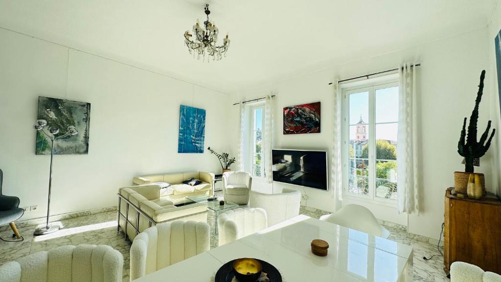 Elle comprend un salon doté d'un mobilier blanc et d'un lustre. dans l'établissement Spacious 3 BR flat Nice center - magnificent view, à Nice