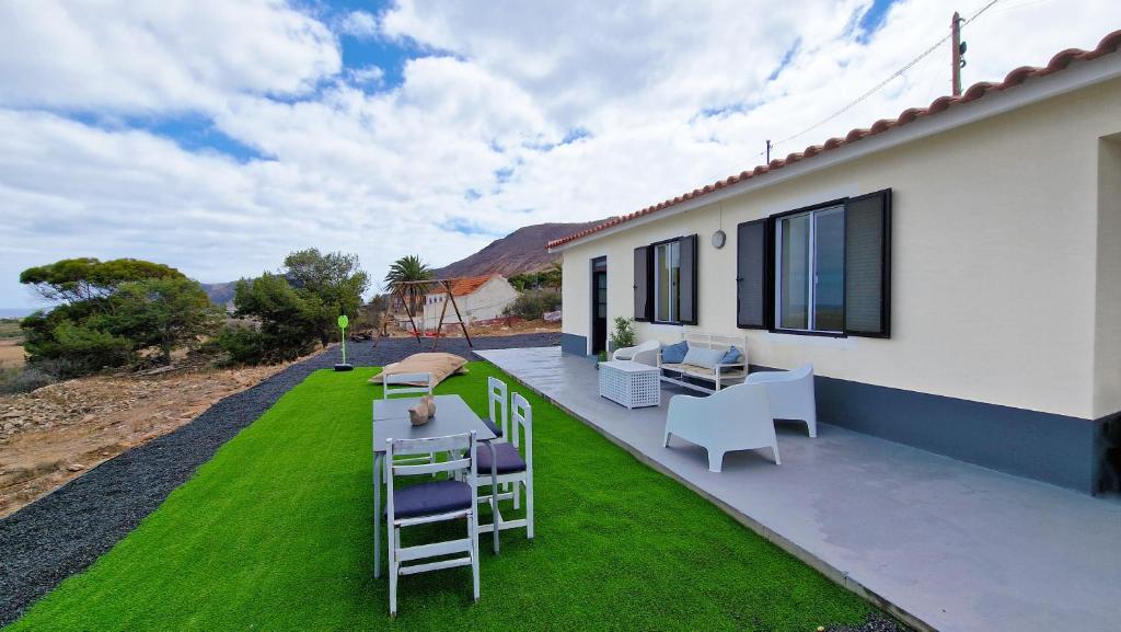 een terras met stoelen, een tafel en gras bij Casa da Ponta by Casas dos Lebre in Porto Santo