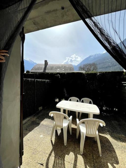 une table et des chaises blanches sur une terrasse avec des montagnes dans l'établissement l'isard, à Luz-Saint-Sauveur