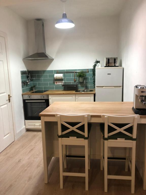 a kitchen with a wooden table with two chairs at Central Sligo Townhouse in Sligo