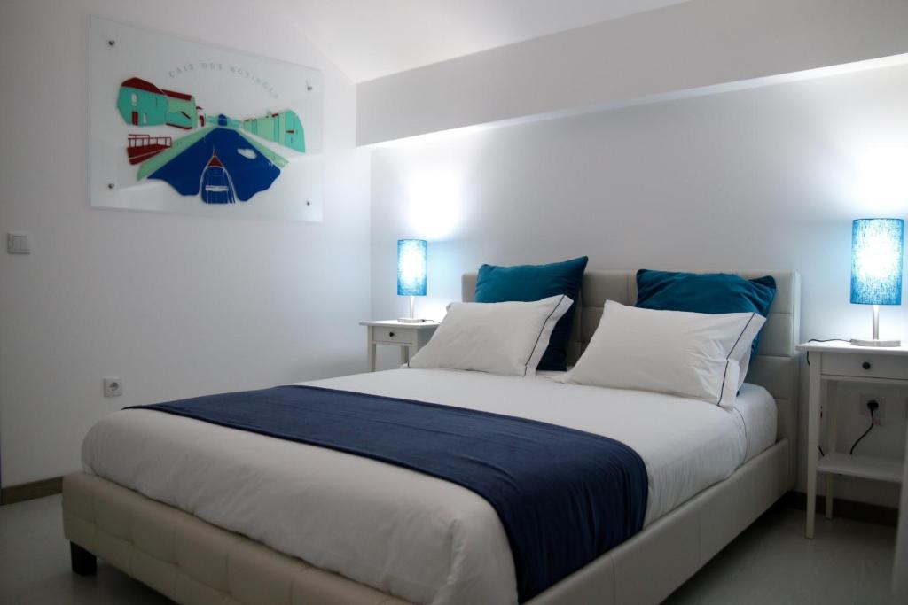 Casa do Cais في أفيرو: غرفة نوم بسرير كبير ومخدات زرقاء وبيضاء