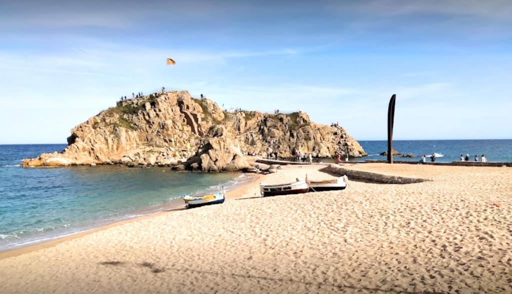 einen Strand mit Booten auf dem Sand neben dem Wasser in der Unterkunft ALQUILER PISO BLANES con VISTAS AL MAR in Blanes