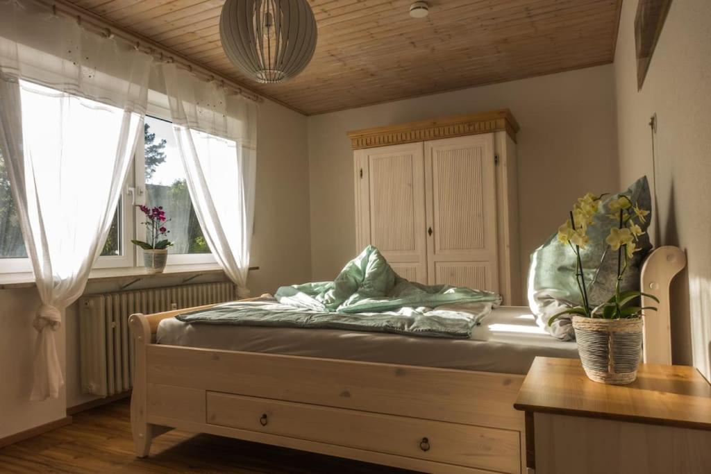 a bedroom with a bed with a dresser and two windows at Landhaus Fazenda auf dem Härtsfeld in Dischingen