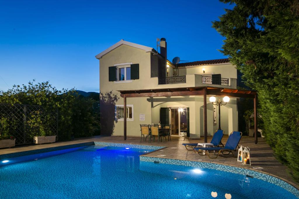 a villa with a swimming pool in front of a house at Thalia Villas in Trapezaki