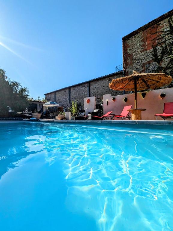 une grande piscine avec un parasol et des chaises dans l'établissement Le Cèdre 1830 Maison d'hôtes de charme et spa, à Saint-Féliu-dʼAvall