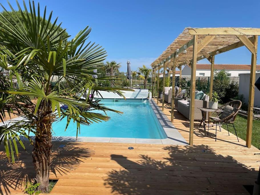 une piscine dans une cour avec un palmier dans l'établissement Villa de charme piscine chauffée St Pierre Oléron, à Saint-Pierre-dʼOléron