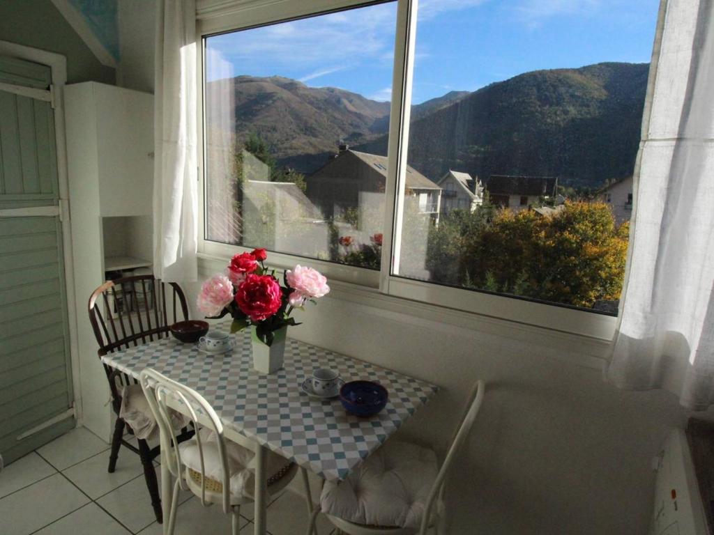 a table with a vase of flowers and a window at Appartement T3 50m² pour 4 pers. avec Wifi et animaux admis à Luchon - FR-1-313-205 in Luchon