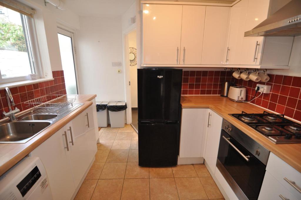 a kitchen with white cabinets and a black refrigerator at Exeter Quay & City Centre St Leonards in Exeter