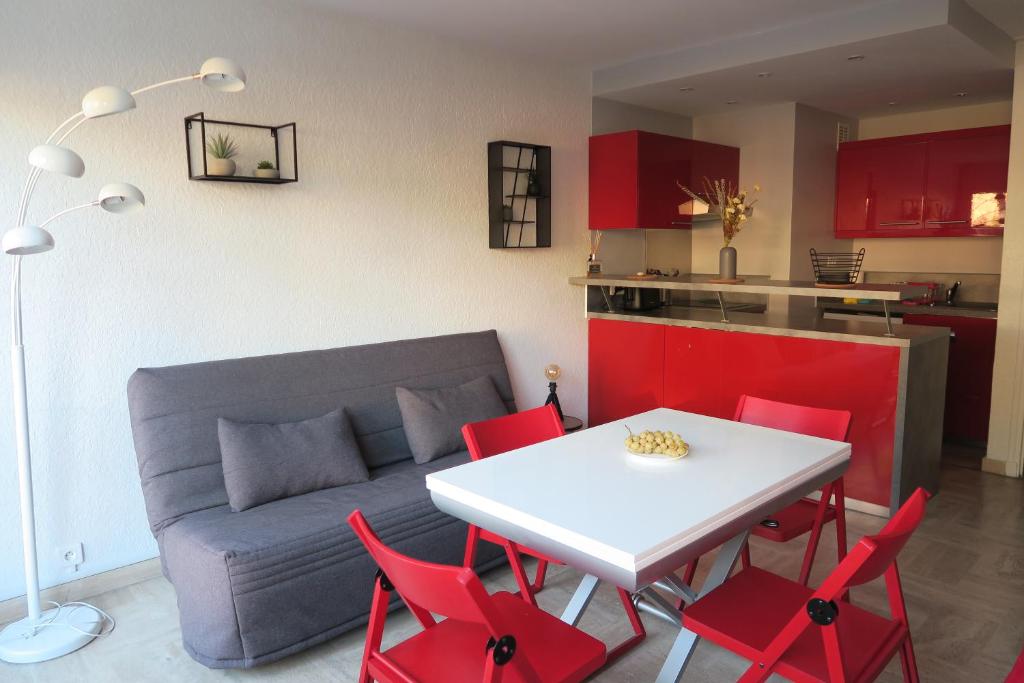 un salon avec une table et des chaises rouges dans l'établissement Grand studio lumineux Boulouris, plage 5min à pied, à Saint-Raphaël