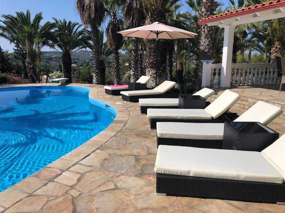 a swimming pool with lounge chairs and an umbrella at Casa di Stephanie - Petrothalassa - Porto Heli in Kranidi