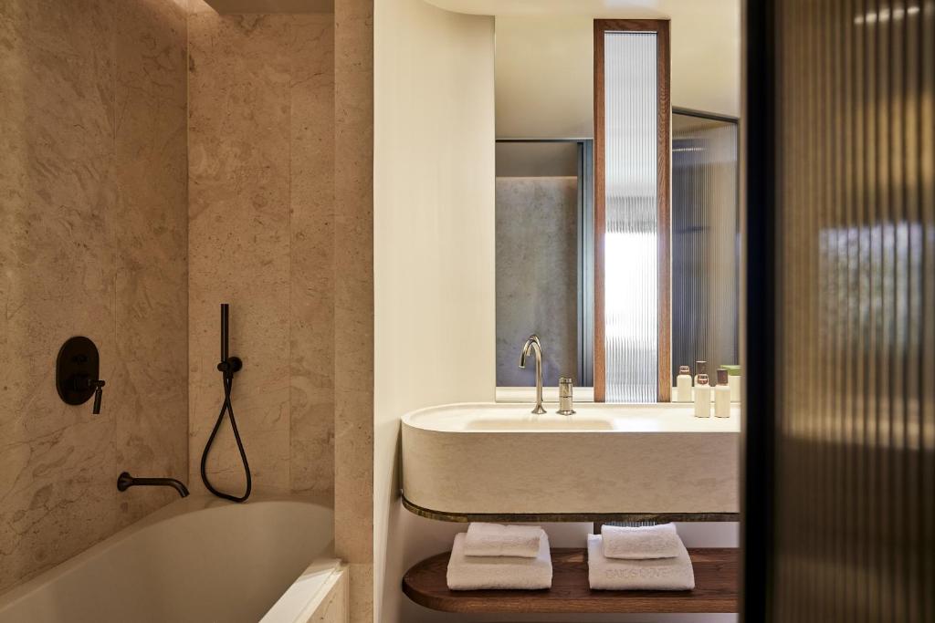 a bathroom with a sink and a tub and a mirror at Daios Cove in Agios Nikolaos