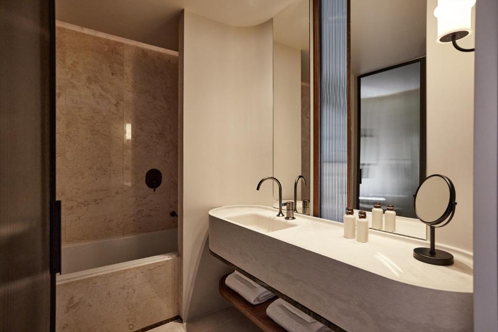 a bathroom with a sink and a tub and a mirror at Daios Cove in Agios Nikolaos