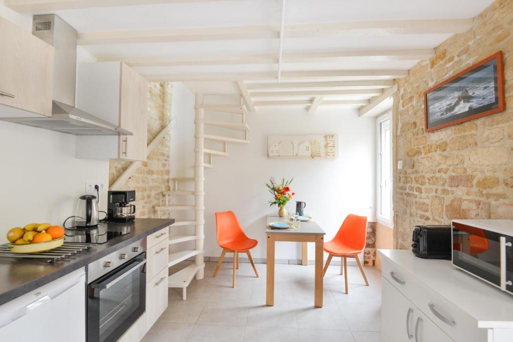 - une cuisine avec des armoires blanches et des chaises orange dans l'établissement L'Écrin de Douvres - Charmante maison pour 2p, à Douvres-la-Délivrande