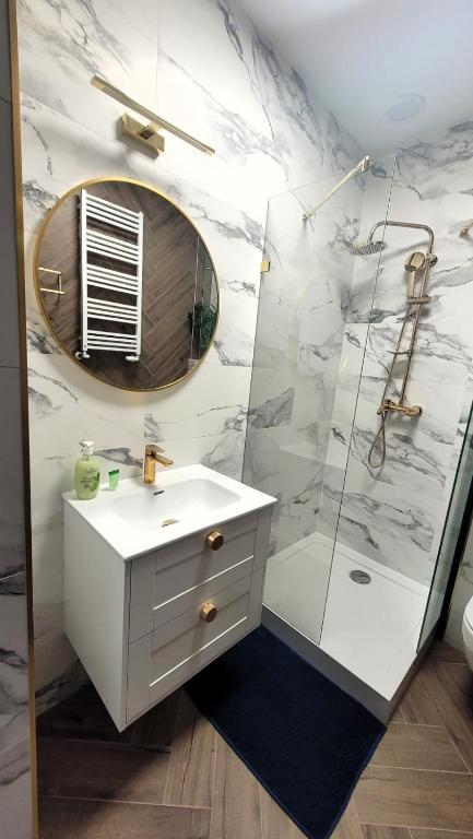 a bathroom with a sink and a shower with a mirror at APARTAMENT JARACZA 28 Nr 3 in Słupsk