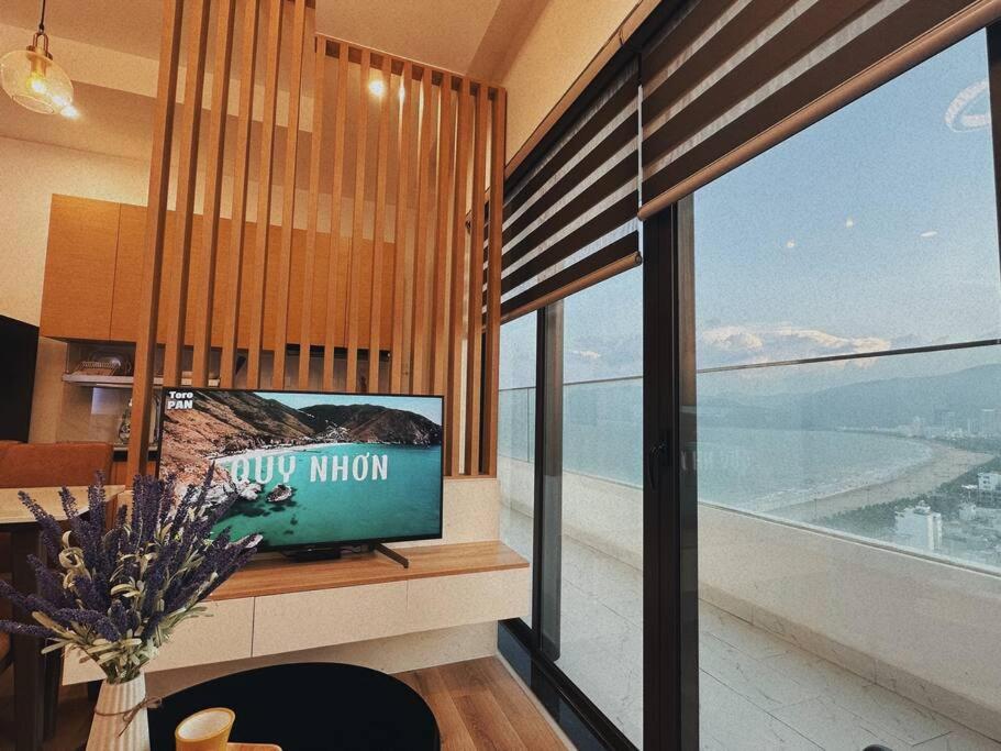 un salon avec une télévision et une grande fenêtre dans l'établissement BBnB Home - Mai's House, à Quy Nhơn