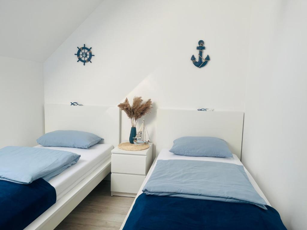 2 bedden in een kamer met witte muren en blauwe kussens bij Apartament DWIE RYBKI in Pobierowo