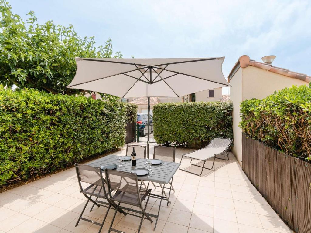 une table et des chaises avec un parasol sur une terrasse dans l'établissement Pavillon 3P climatisé, piscine, terrasse, proche plage, 6 pers., Narbonne - FR-1-409-12, à Narbonne
