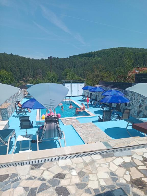 a swimming pool with blue umbrellas and people in it at Apartmani Gocki Raj 2024 Vrnjačka Banja in Vrnjačka Banja