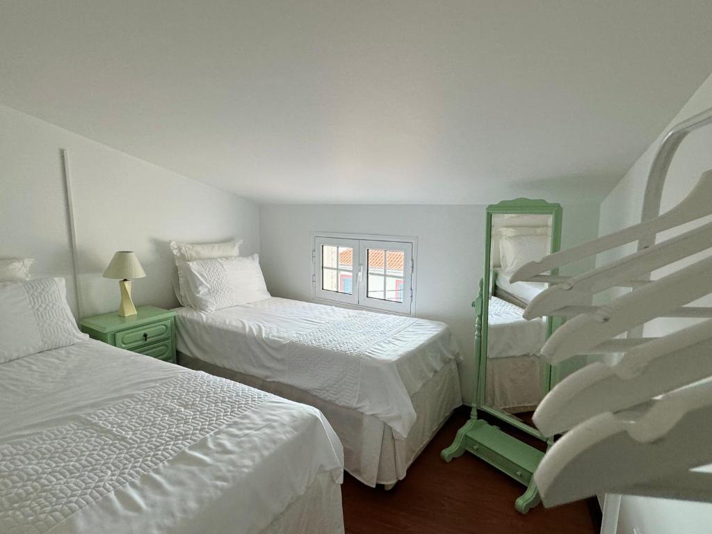 Un dormitorio con dos camas y una escalera con espejo. en Arco Apartment, en Arco da Calheta