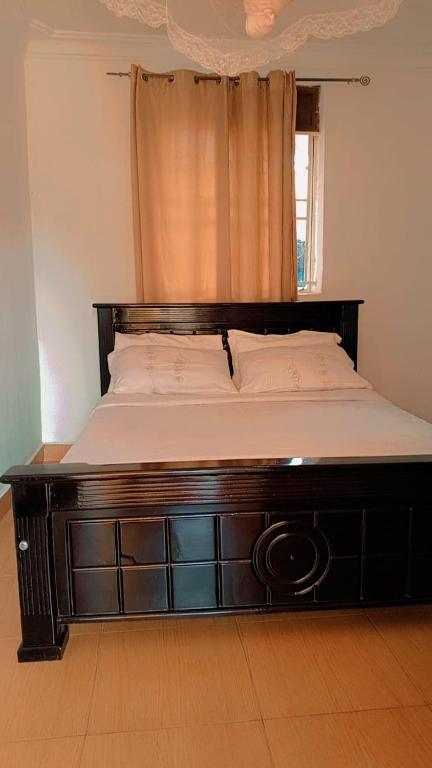 a bed with a wooden frame in a room with a window at Nandyowa Guesthouse in Kampala