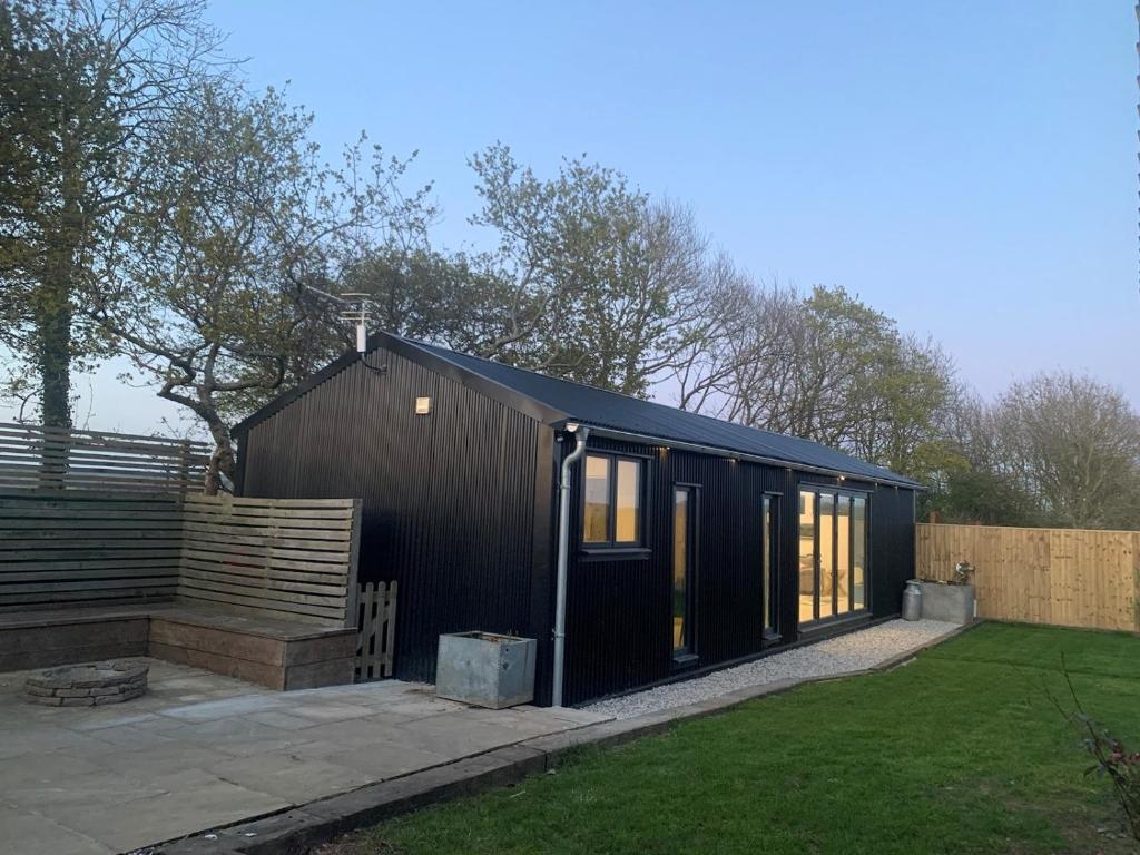 a black building with windows and a fence at Lavish Dorset countryside retreat in Bradpole