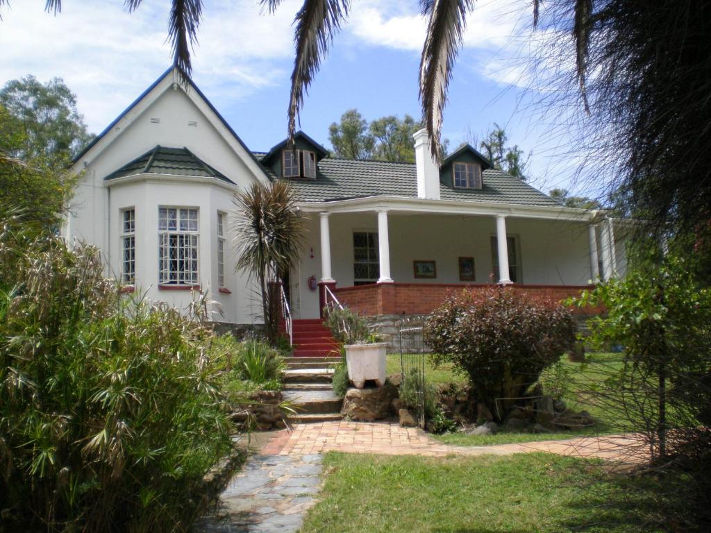 a white house with a palm tree at Ashtonville Terraces Guesthouse in Estcourt