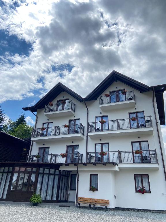 a white building with balconies and a bench in front of it at Casa Complex Borsa in Statjunea Borsa