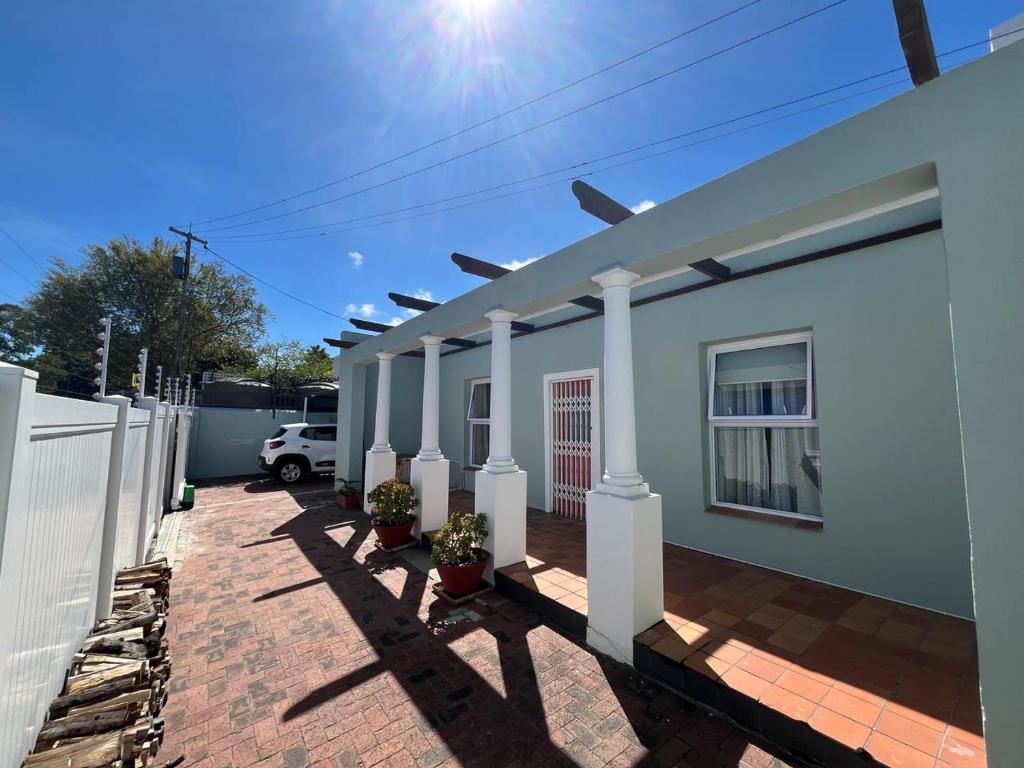 a white house with a fence and a driveway at Sage Cottage in Somerset West