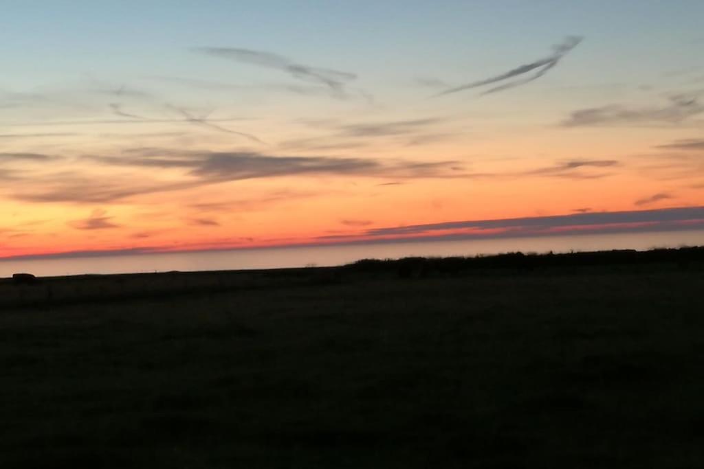 un coucher de soleil sur un champ avec un avion dans le ciel dans l'établissement villa nenette vue mer location à la semaine, à Veulettes-sur-Mer