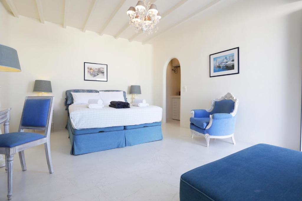 a bedroom with a bed and two blue chairs at Blue Studio at Cavo Delos in Agios Ioannis Mykonos