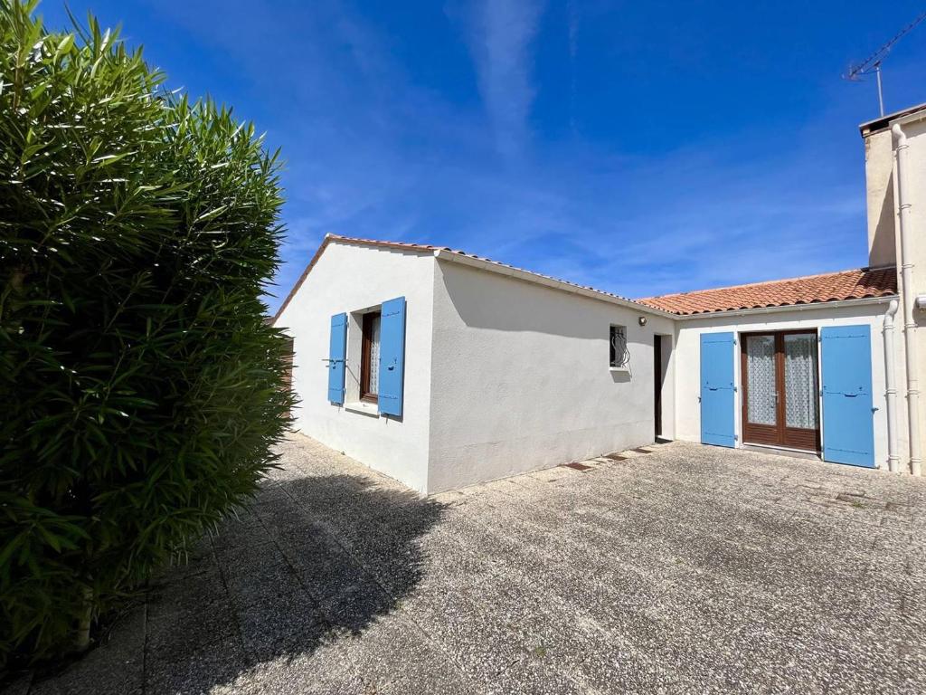 une maison blanche avec des portes bleues et une cour dans l'établissement Charmante maison 6 pers., 2 chambres, proche plage et commerces, jardin clos, terrasse, barbecue - FR-1-246A-345, à La Cotinière