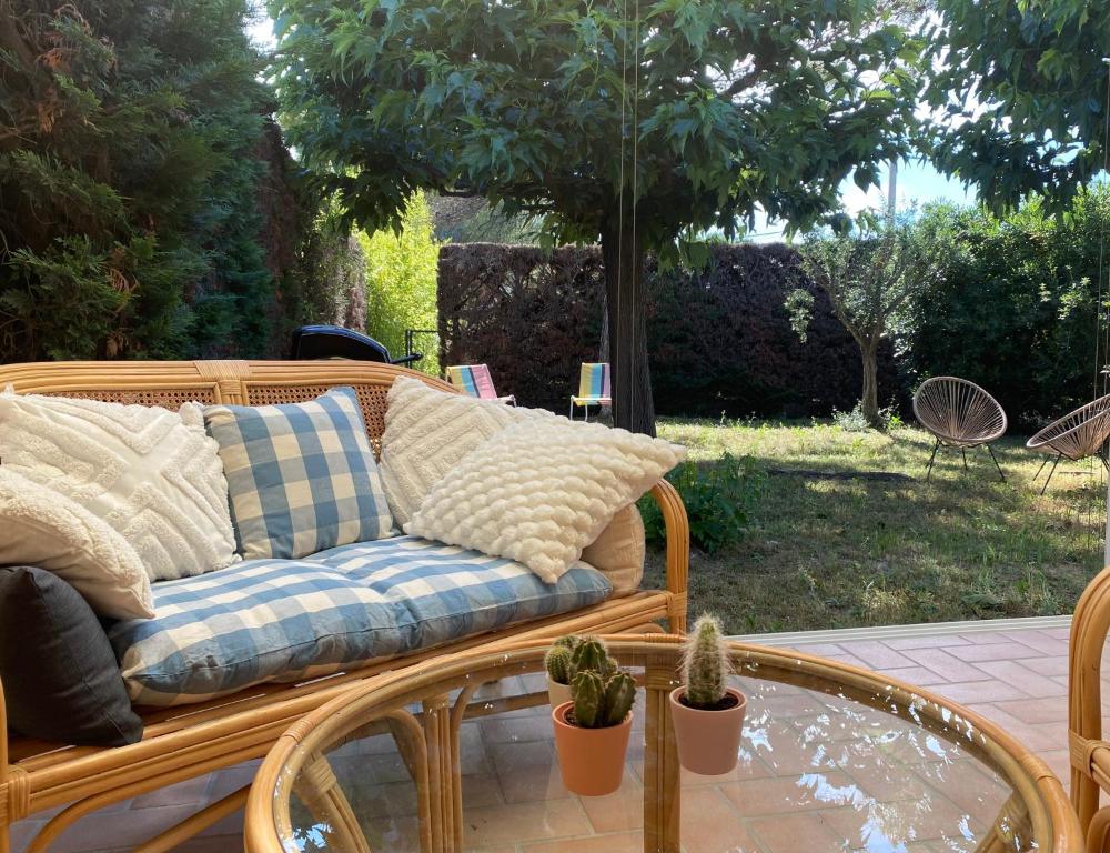 un canapé en osier assis sur une terrasse avec une table en verre dans l'établissement Inspiration maison entière avec jardin, à Pernes-les-Fontaines